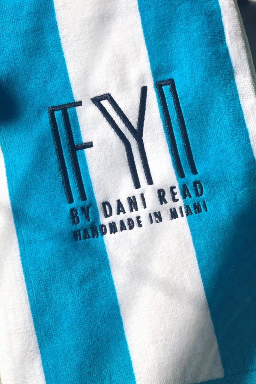 Close-up of a blue and white striped towel with 'FYI by Dani Read' branding.
