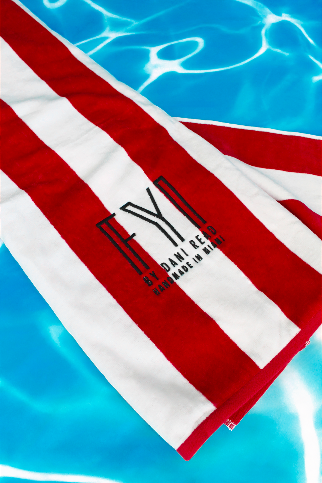 Red and white striped towel with a logo on a blue water background